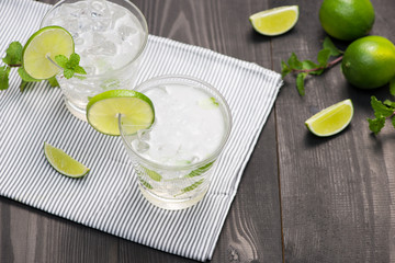 Fresh cocktail with lime, ice and mint on a rustic background. Copy space, top view