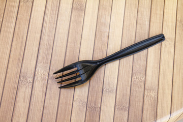 Plastic utensils, one pair put on a wooden table.