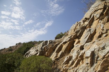 Naklejka premium Rocks, green plants and sky with clouds landscape