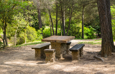 Naklejka premium Une table en pierre avec les bancs pour le pique-nique dans le forêt. Parc naturel