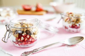 Diet dessert with yogurt, granola and pomegranates in a glassware. Horizontal. Rose tablecloth,...