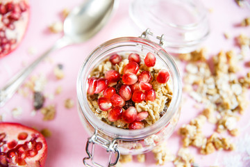 Diet dessert with yogurt, granola and pomegranates in a glassware. Three jars. Top view. Rose tablecloth, silver spoon. Closeup.