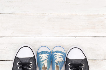 Daddy's boots and baby's sneakers, on white wooden background, father’s day concept.
