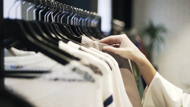 Close up of a young woman s hand choosing clothes to buy in a shop. Locked down real time close up shot