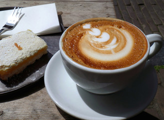 Hot coffee with lemon tart served on wooden table at the outdoor seating