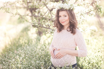 Obraz premium Smiling pregnant woman making heart with fingers in meadow. Looking at camera. Motherhood. Maternity. 20s.