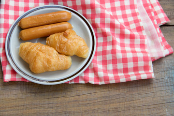 Close-up Croissant and sausage on plaid red napkin. Top view