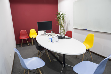 Office empty meeting room with liquid crystal display and telephone. Colorful  chairs and board.