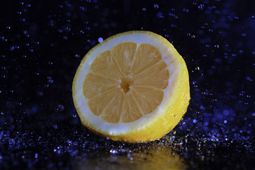 halbe Zitrone auf dunkem Hintergrund mit vielen Wassertropfen