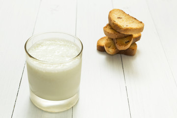 Dietary breakfast, sour yogurt in a glass beaker and crackers with raisins on a white table.