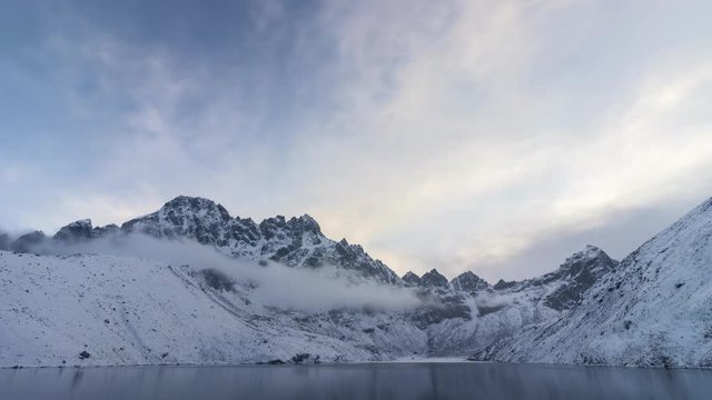 Time lapse of lake and snowy mountains in the evening. Blue sky with clouds. Gokyo, Nepal.