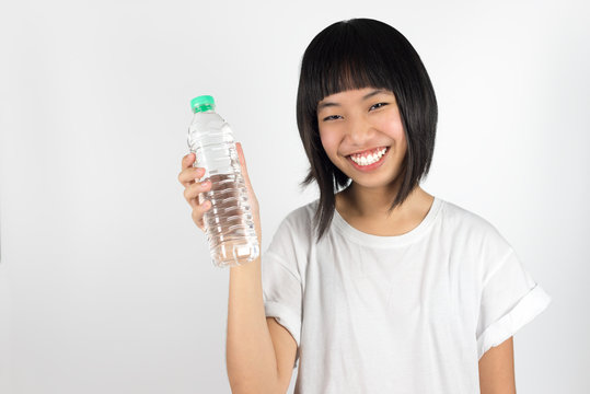 Young Beautiful Asian Teenage Girl Holding Bottle Of Water Isolated Against White Background