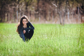 Young girl collects field plants on a spring lawn.