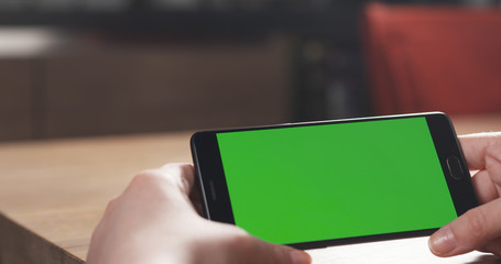 female teen girl using smartphone with green screen sitting at the table, 4k photo