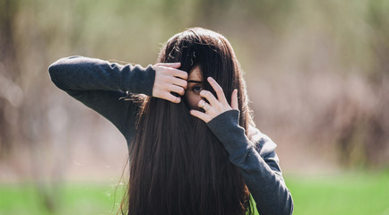 A young girl looks out of her long hair with fear. 