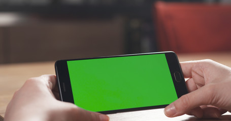 female teen girl using smartphone with green screen sitting at the table, 4k photo