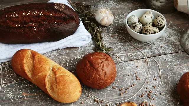 Different types of bread on wooden table dusted with flour. Slow pan. Concept of natural food.