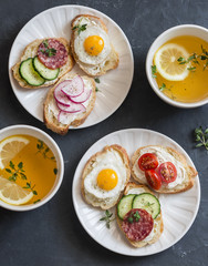 Mini sandwiches with cream cheese, vegetables, quail eggs, salami and green tea with lemon and thyme. Sandwiches with cheese, cucumber, tomatoes, radish, thyme, lemon zest, fried quail eggs