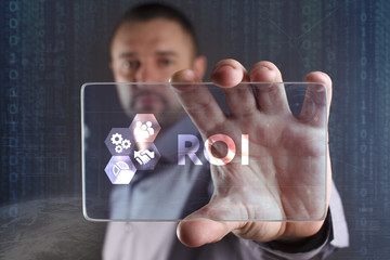 Business, Technology, Internet and network concept. Young businessman working on a virtual screen of the future and sees the inscription: ROI