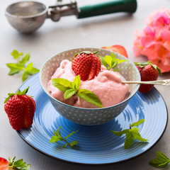 Home made strawberry ice cream in bowl with min leaves