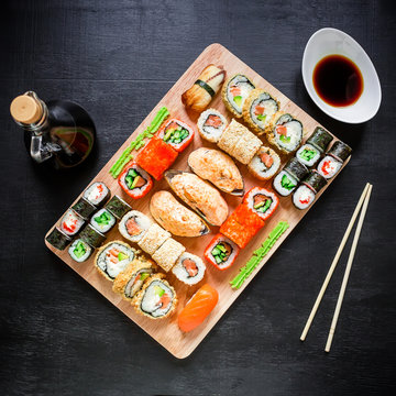 Restaurant food. Sushi rolls, soy sauce and traditional chopsticks on a black background. Top view. Flat lay.
