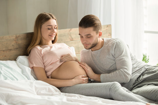 Young couple expecting baby relax on bed indoors