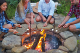 Company of young people holding sticks with marshmallows