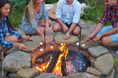 Company of young people holding sticks with marshmallows