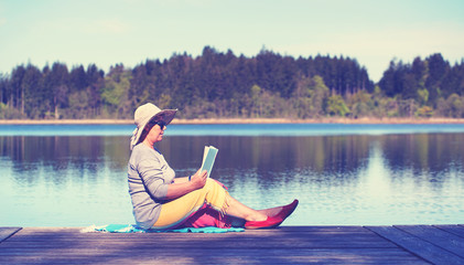 ältere Frau beim Lesen am See