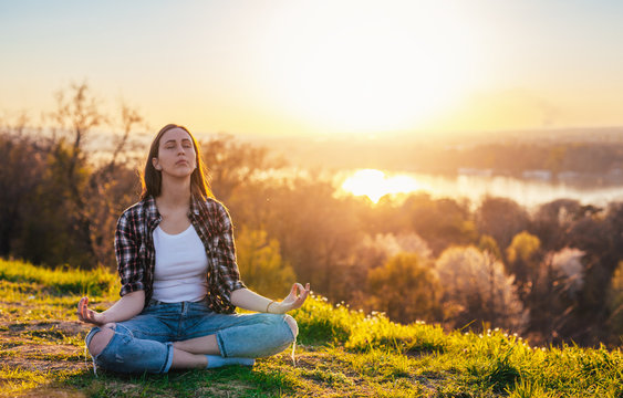 Woman relaxing on the sunset light in the mountain doing yoga lotus position