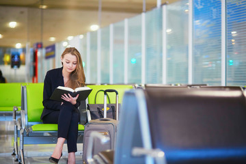 Woman in international airport terminal, reading book