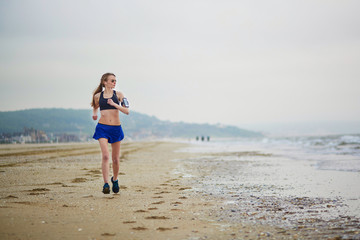 Fototapeta na wymiar Young fitness running woman jogging on beach