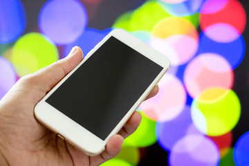 Hand holding mobile smart phone with blank screen , bokeh background - mockup template