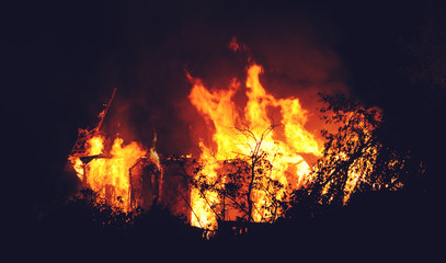 Arson or nature disaster - burning fire flame on wooden house roof