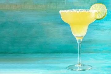 Fotobehang Cocktail Lemon Margarita-cocktails op levendig turkoois met copyspace