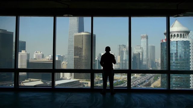 a businessman outlook business building from window.