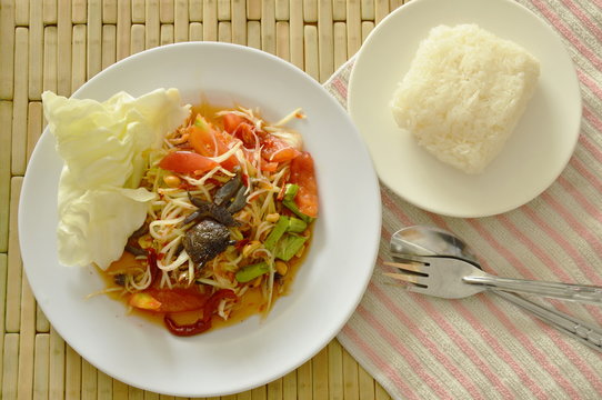 Somtum Thai spicy green papaya and black pickled crab salad eat with sticky rice