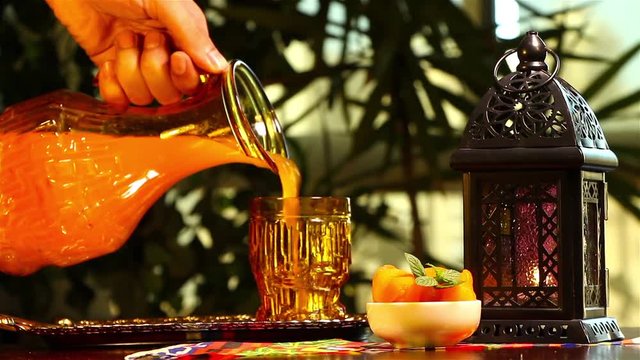 Woman pouring Qamar El Din (Apricot Juice) into a glass , ready for happy breakfast in Ramadan