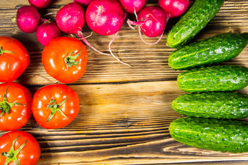 Fresh cucumbers, radishes and tomatoes on the wooden table