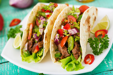 Mexican tacos with beef in tomato sauce and salsa