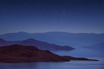 Fototapeta premium Hills and mountains are reflected in the lake at night.