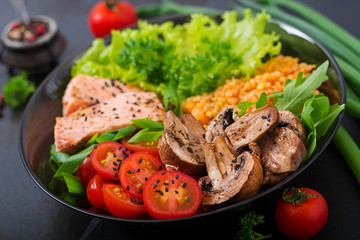 Healthy salad with salmon, tomatoes, mushrooms, lettuce and lentil on dark background