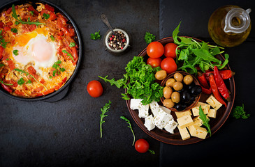 Breakfast. Fried eggs with vegetables - shakshuka in a frying pan on a black background in the Turkish style. Flat lay. Top view