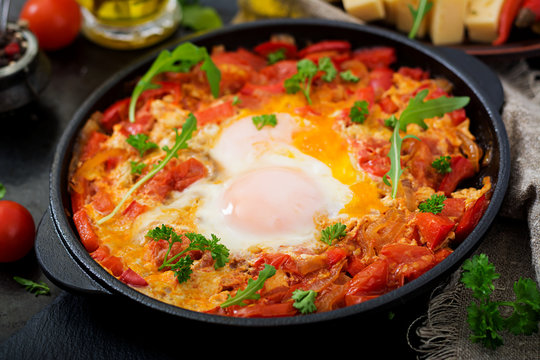 Breakfast. Fried eggs with vegetables - shakshuka in a frying pan on a black background in the Turkish style.
