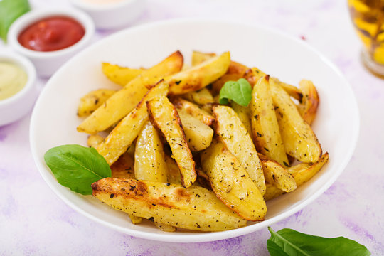 Ruddy Baked potato wedges with  herbs on a light background.