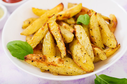 Ruddy Baked potato wedges with  herbs on a light background.
