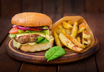 Big sandwich - hamburger with juicy beef burger, cheese, tomato,  and red onion on wooden background