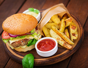 Big sandwich - hamburger with juicy beef burger, cheese, tomato,  and red onion on wooden background
