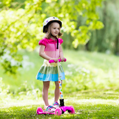 Little girl riding a colorful scooter