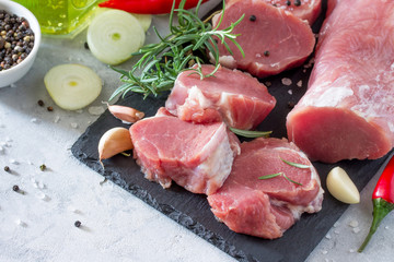 Fresh meat fillets raw with chili, onions, spices and rosemary on a cutting board. Copy space.